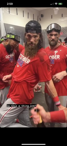 a group of baseball players standing next to each other wearing red shirts and grey pants