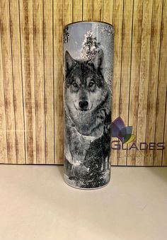 a black and white photo of a wolf on a tumbler cup with wood background