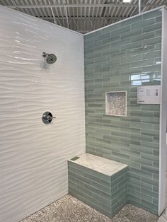 a walk in shower sitting next to a white tiled wall and floor with grey tiles