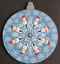 an ornament with snowmen on it is hanging from a hook in the shape of a circle