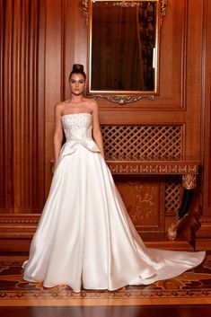 a woman standing in front of a mirror wearing a wedding dress