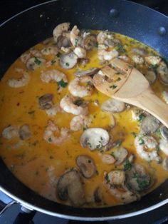 a skillet with shrimp and mushrooms cooking on the stove