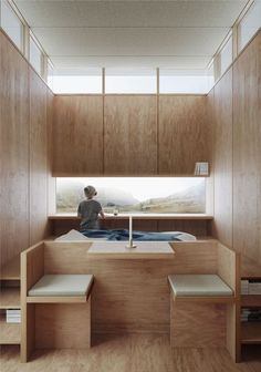 a person sitting on a bed in a room with wooden walls and shelves around them