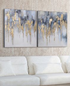 two paintings are hanging on the wall next to a white couch in a living room