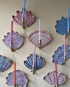 several decorative blue and red plates hanging from hooks on a wall with candles in them