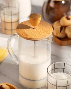 a glass pitcher filled with milk next to cookies