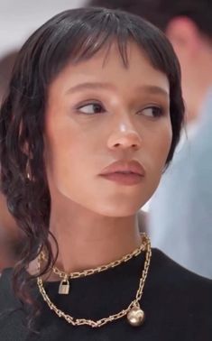 a close up of a person wearing a black shirt and gold chains on her neck