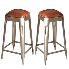 two metal stools with brown leather seats