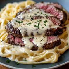 steak and noodles on a plate with gravy drizzled over them