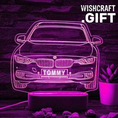 a car with the name tommy on it is lit up in purple and has a potted plant next to it