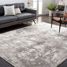 a living room filled with furniture and a large rug on top of a hard wood floor