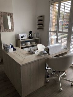 a room with a desk, chair and window covered in shutters is seen here