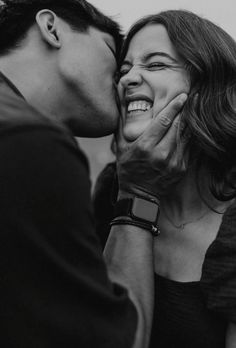 a man kissing a woman's face with her hand on her cheek while she smiles