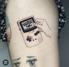 a person with a tattoo on their arm holding a gameboy