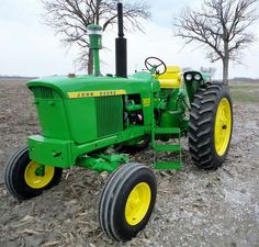 a green tractor parked on top of a dirt field