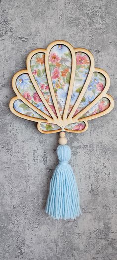 a decorative wall hanging made out of wood with a blue tassell and flower design