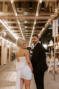 a man and woman standing next to each other in front of a building with lights