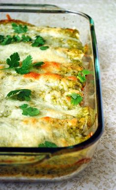 a casserole dish with vegetables and cheese in it sitting on a white tablecloth