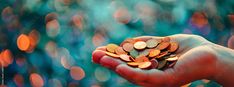 a person's hand holding some coins in front of blurry boke background