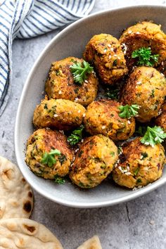 a bowl filled with meatballs covered in parsley on top of pita bread