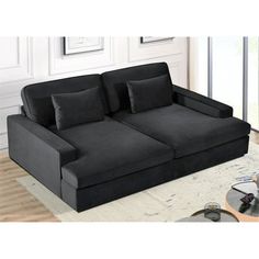 a black couch sitting on top of a white rug in a living room next to a window