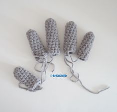 four crocheted mittens tied together on a white surface with the word hooked written in blue