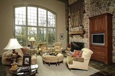 a living room filled with lots of furniture and a fire place in front of a large window