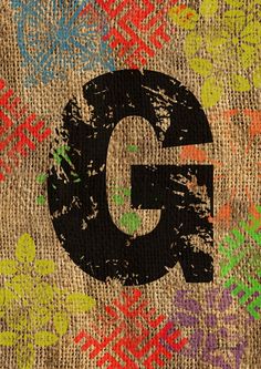 the letter g is painted on a piece of burlock with multicolored dots