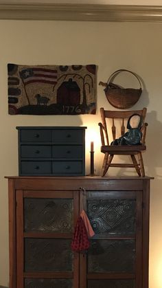 a wooden chair sitting on top of a dresser next to a wall mounted painting and lamp