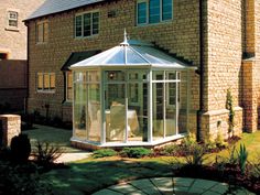 a large brick building with a glass enclosed patio area in front of it and a white gazebo on the side