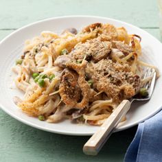 a white plate topped with pasta and meat covered in sauce next to a glass of milk