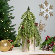 a small christmas tree sitting in a pot on top of a table next to other decorations