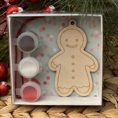 a wooden ginger ornament in a clear box next to some christmas decorations and baubles