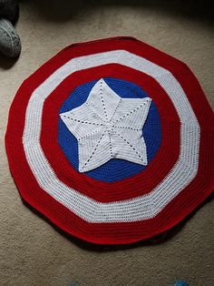 a red, white and blue crocheted rug with a star on it sitting on the floor