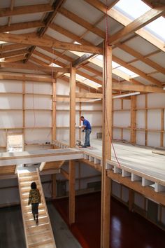 a man standing on top of a wooden floor next to a ladder in a building