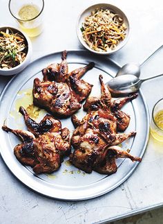 a plate full of chicken wings and bowls of food on a table with utensils