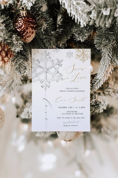 the wedding stationery is surrounded by pine cones and evergreen branches, which are accented with gold - colored ornaments