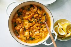 a pan filled with food next to a bowl of lemon wedges