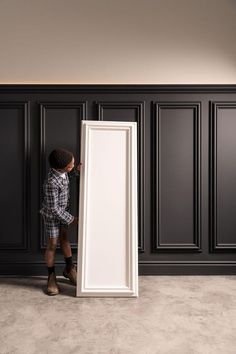 a young man standing in front of an empty white framed canvas on the floor,