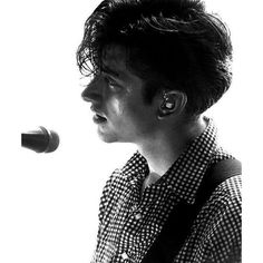 a man standing in front of a microphone with ear buds on his ears and looking off into the distance