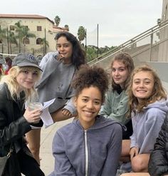 a group of young women sitting next to each other on top of a cement bench