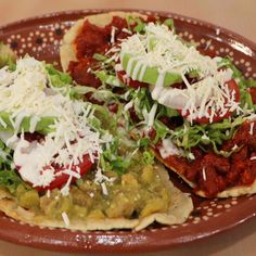 two tortillas topped with lettuce and cheese on a brown platter