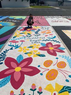 a woman kneeling on the ground in front of a painted walkway