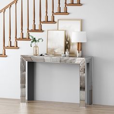 a modern console table in the middle of a room with stairs and pictures on the wall