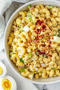 a white bowl filled with macaroni salad next to an egg on the side