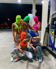 five people in neon colored masks at a gas station