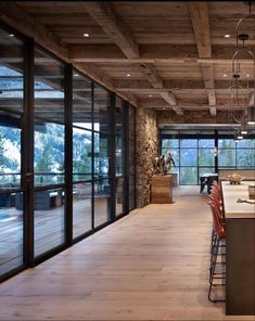 an open kitchen and dining room area with wood flooring, stone walls and large windows