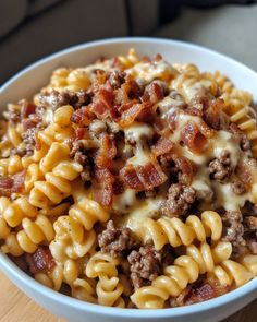 a white bowl filled with macaroni and cheese covered in ground beef, sauce and melted cheese