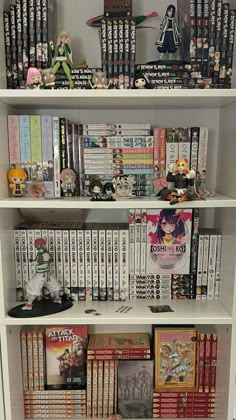 a white book shelf filled with books and anime figurines on top of it