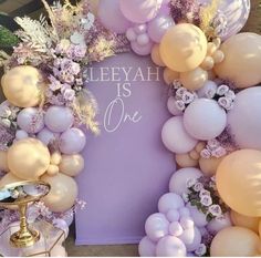 balloons and flowers are arranged around a sign that reads,'llee yah is one '